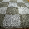 Picture of a rug featuring a checkered pattern in plush material